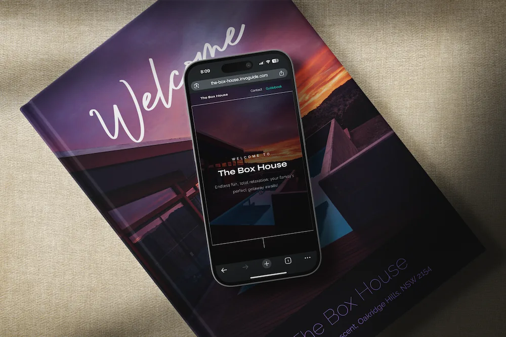 InvoGuide: Digital guidebooks for Airbnbs or vacation rental properties a cell phone with a digital guidebook displayed in it, placed on top of a physical guidebook